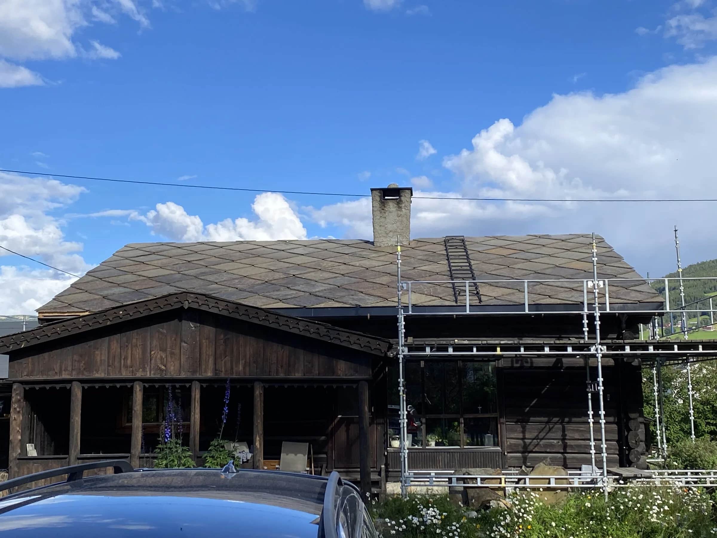 Eldre skifertak med patina og takstige på laftet bygning