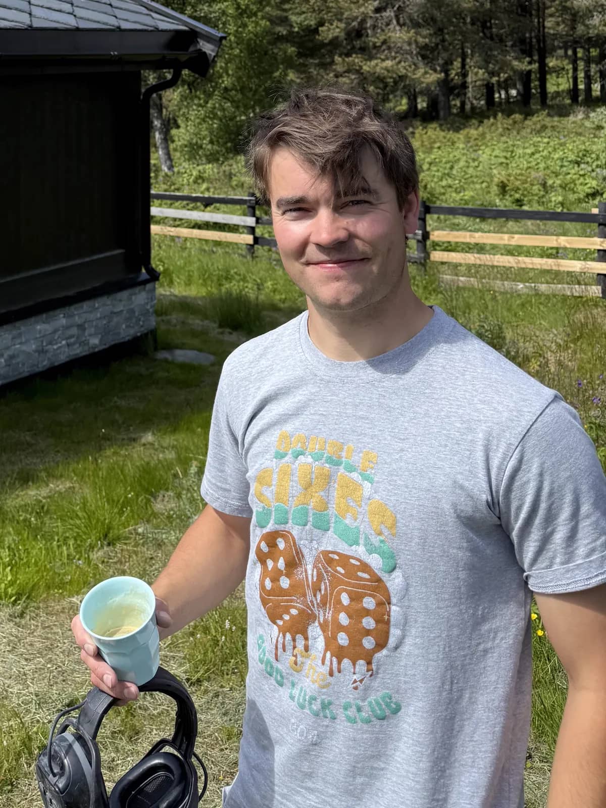 Elias med kaffekopp foran hytte med nylagt skifertak